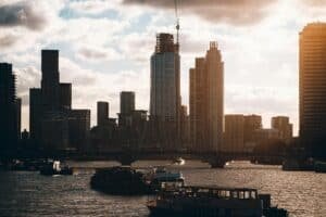 Silhouette of London's skyline against a stunning sunset with boats on the River Thames.