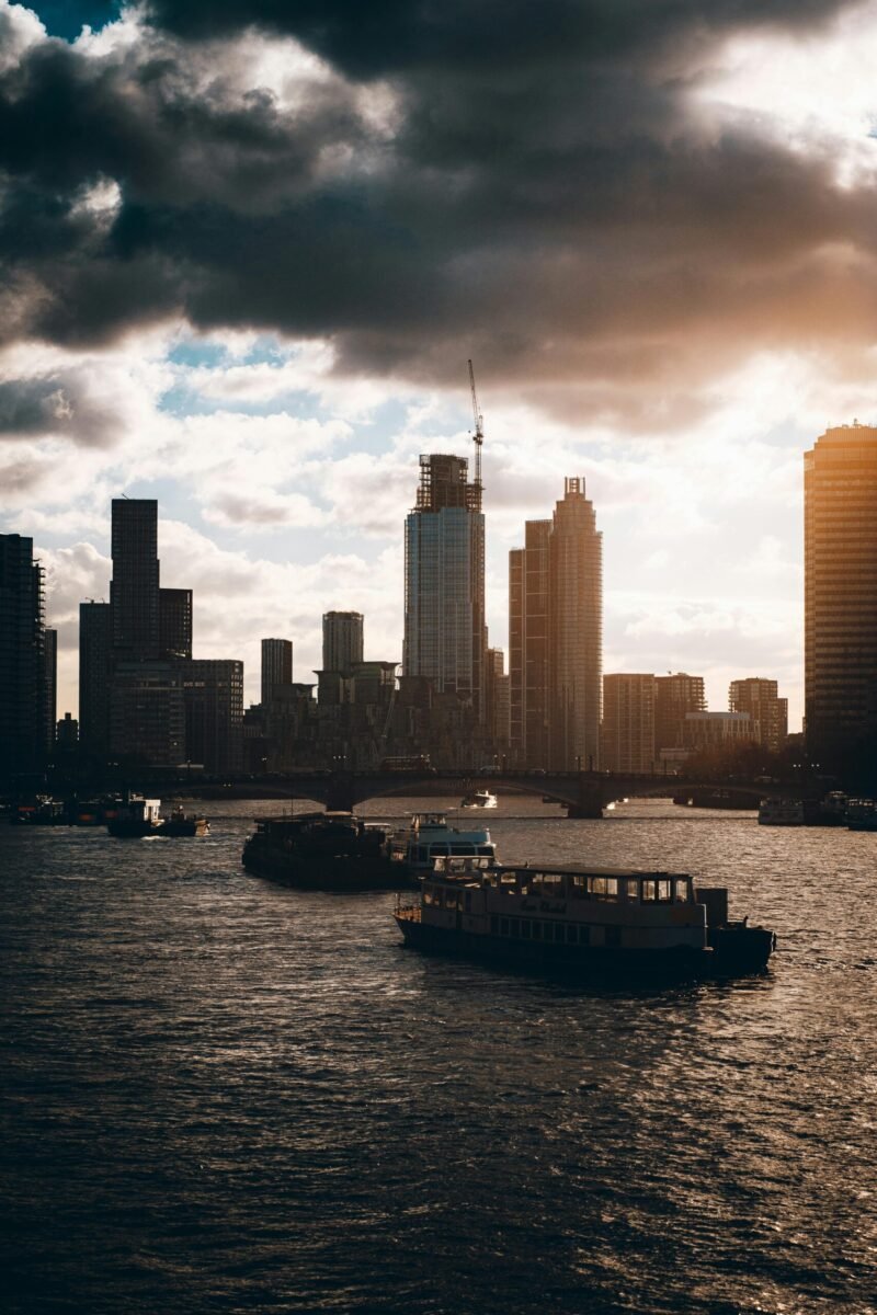 Silhouette of London's skyline against a stunning sunset with boats on the River Thames.