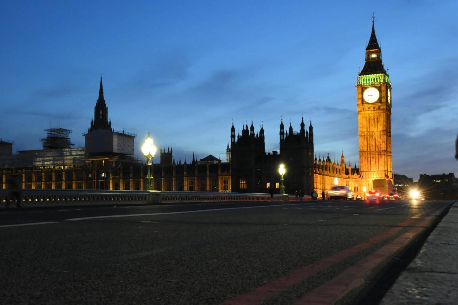Night view of Big Ben and the Palace of Westminster with illuminated city lights and moving traffic.