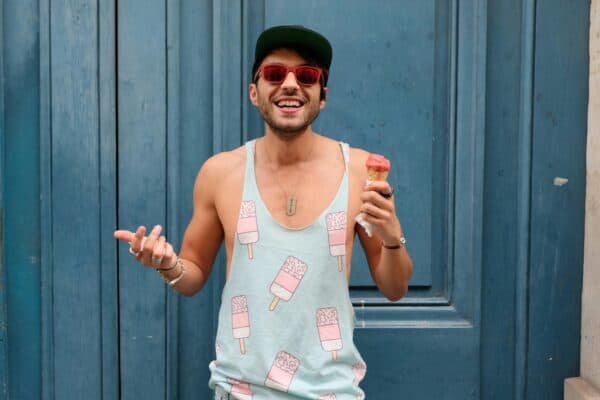 Happy man in Paris enjoying ice cream against a blue door. Fashionable and fun summer vibe.