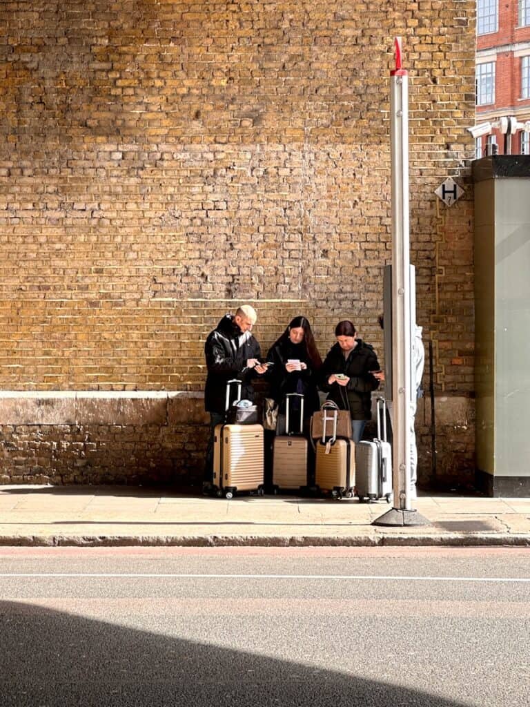 A group of people sitting on a bench next to luggage